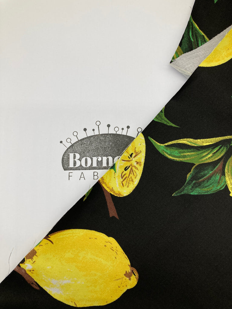 The lemon fabric covering a Bornella Fabrics logo. The fabric is opaque.